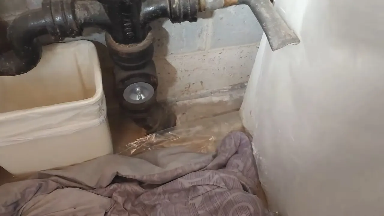Plumber working on an older cast iron drain connection in an Allendale basement