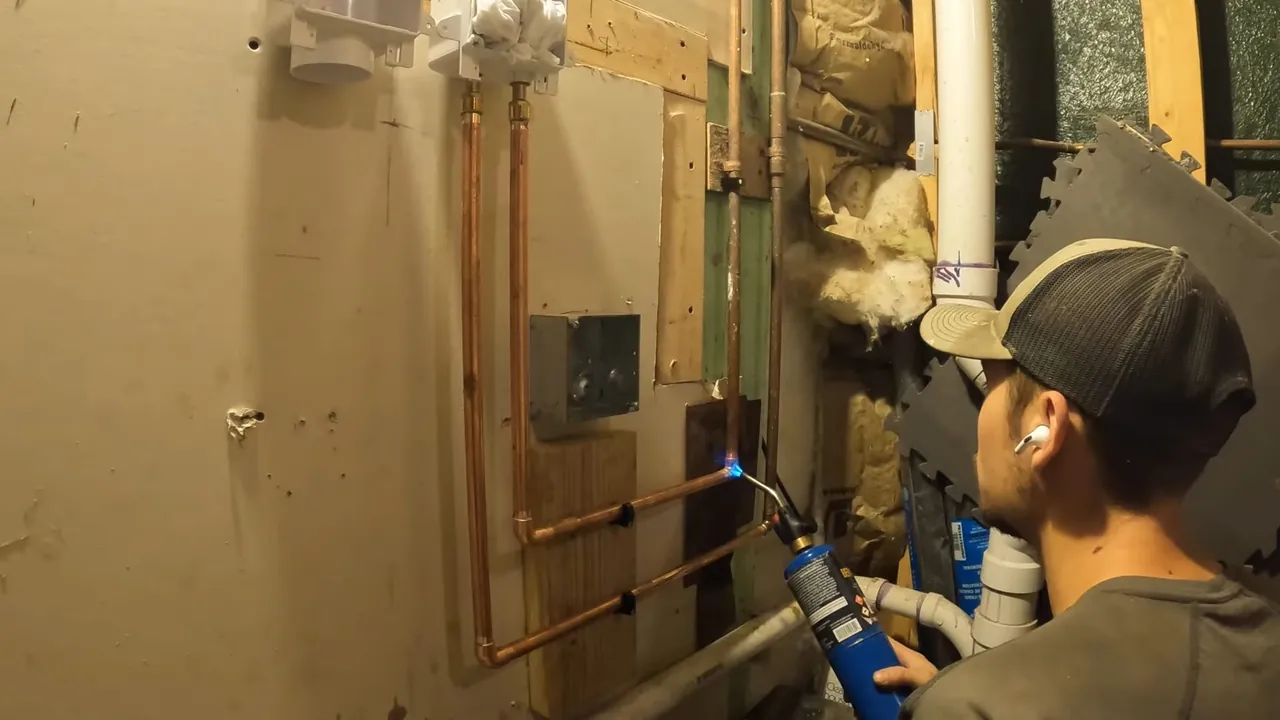 Plumber installing copper laundry supply lines in an Applewood basement