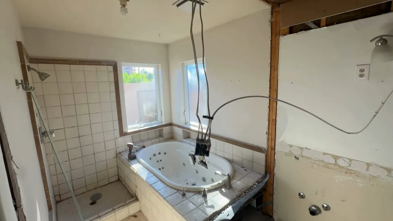 Bathroom renovation with wall surfaces removed to expose drain and supply plumbing