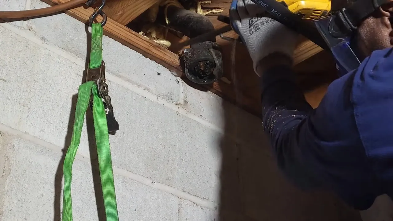Plumber cutting an old cast iron drain pipe during a crawlspace replacement