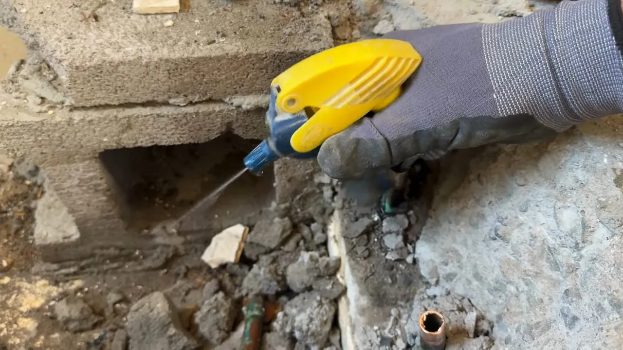 Technician probing a small opening in concrete during a slab leak investigation