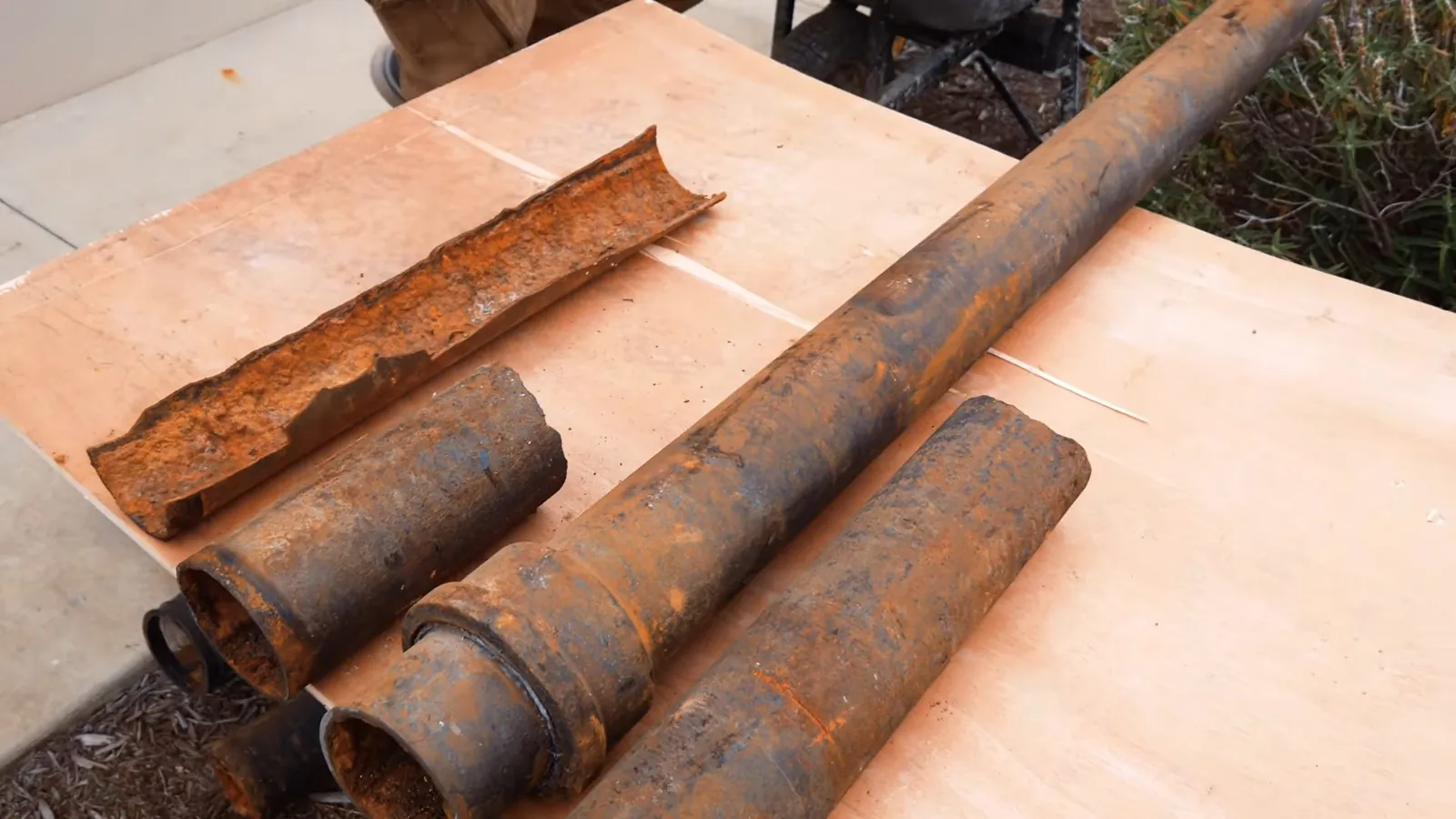 Removed cast iron drain sections with heavy rust and interior buildup from an older plumbing system