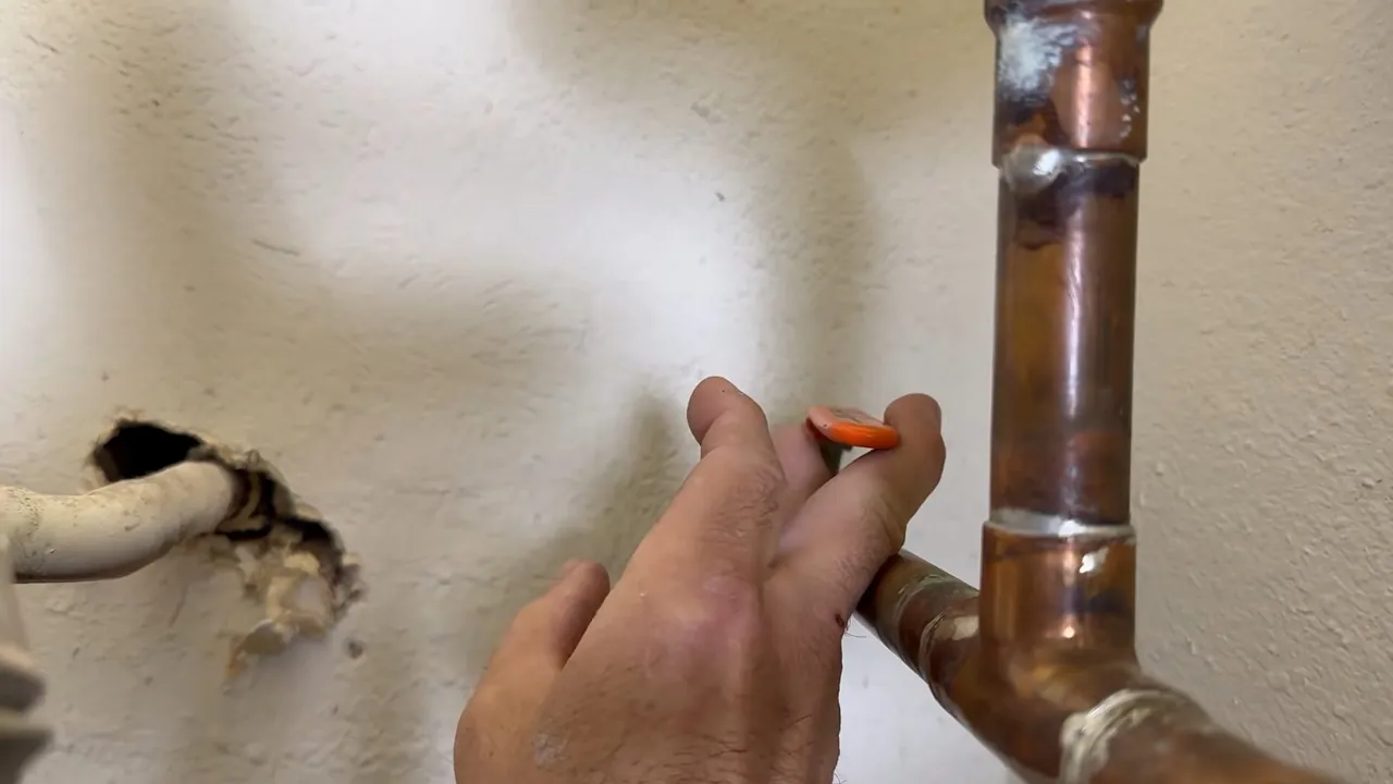 Technician inspecting a copper pipe connection during leak service on Wheat Ridge Eastside
