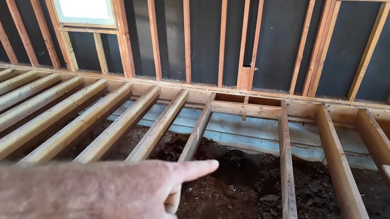 Exposed wall framing and an older cast iron plumbing line during renovation