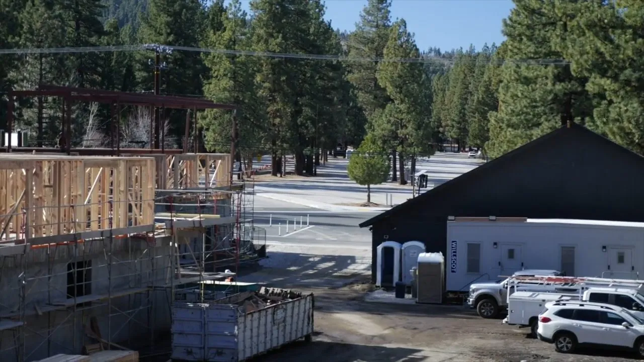 Active plumbing construction site with evergreen-covered foothills in the background