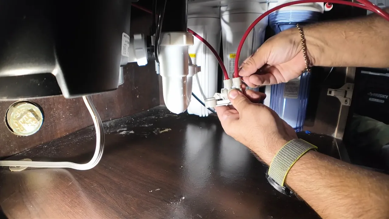 Technician connecting electrical wiring beneath a kitchen garbage disposal