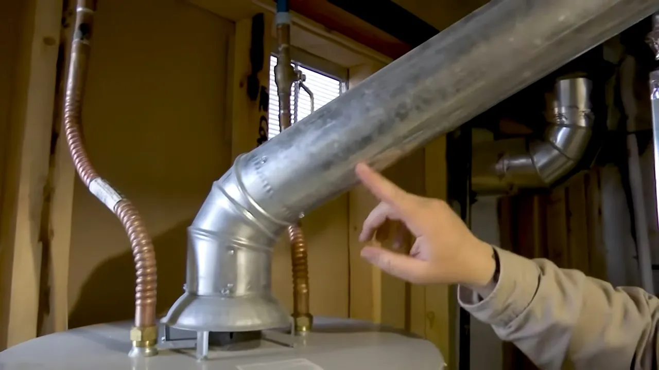 Technician pointing to the vent connector above a water heater in Golden