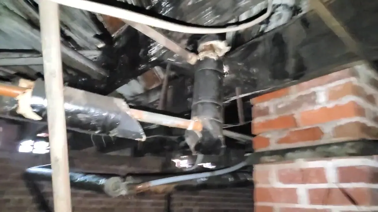 Older drain piping running through a basement with brick foundation walls