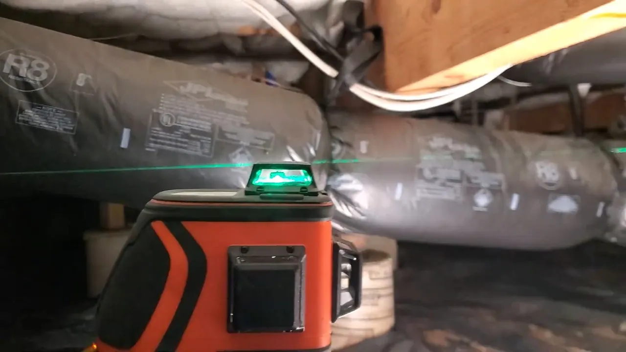 Laser level checking the slope of a crawlspace drain pipe on Wheat Ridge Northside