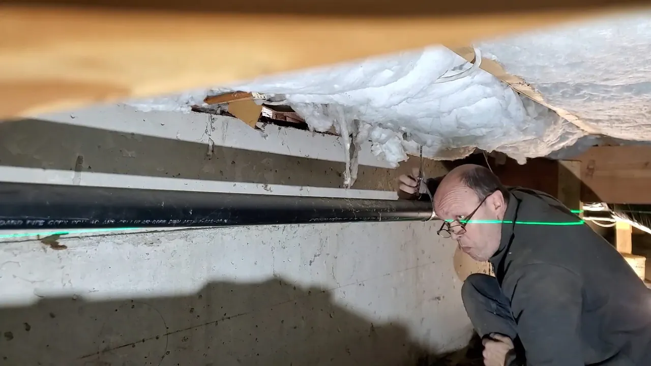 Technician inspecting a drain line beneath a Northwest Denver property