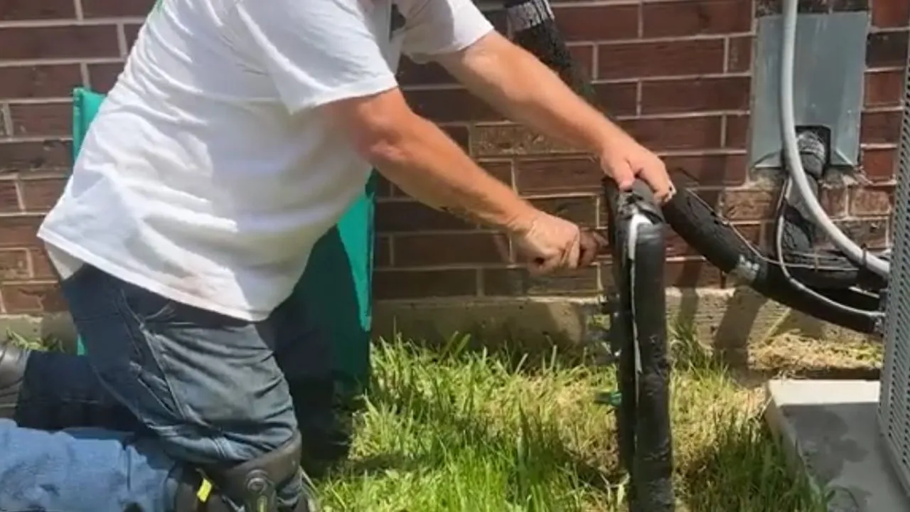 Technician servicing an outdoor backflow preventer beside a home