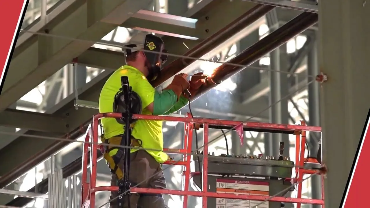 Licensed pipefitter installing an overhead plumbing line from a work platform