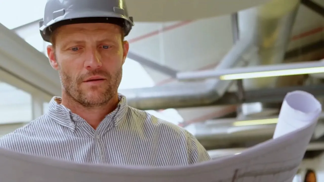 Plumbing contractor in a hard hat reviewing construction plans