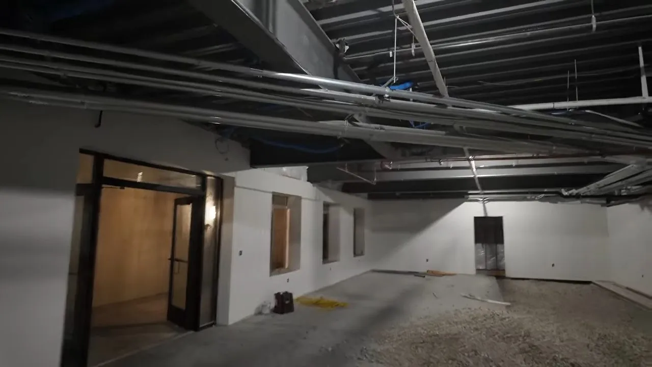 Large plumbing rough-in installed across the ceiling of an open Regis area building