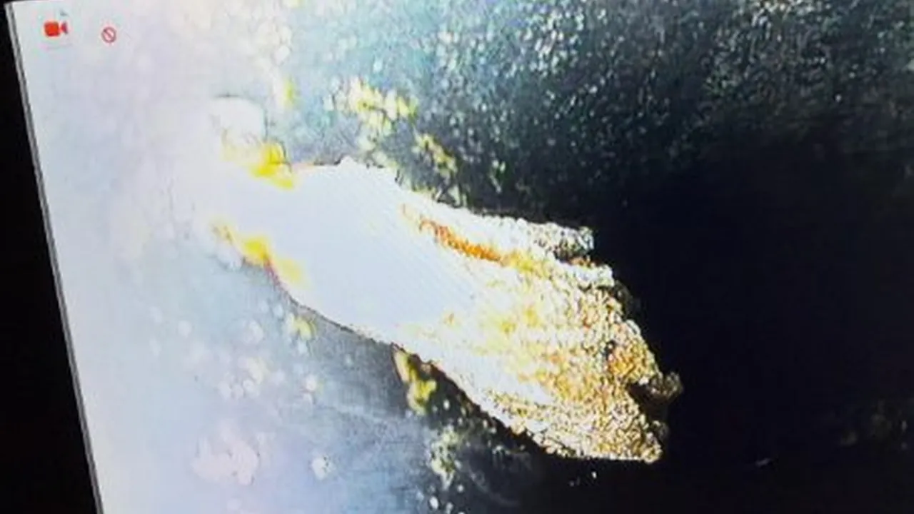 Sewer camera screen showing a pale obstruction inside a dark drain line