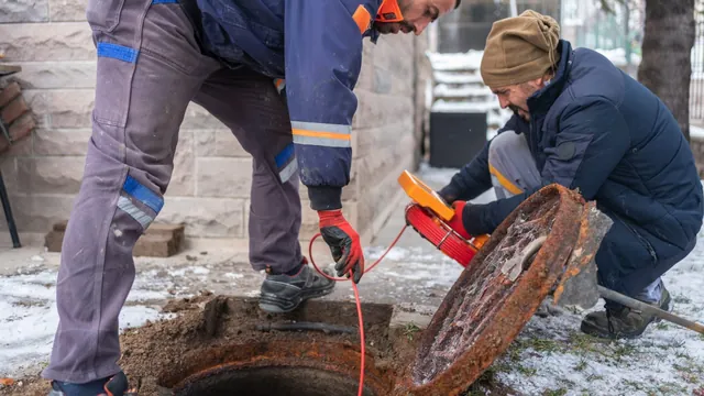 Sewer technicians removing a dense root obstruction from an underground drain line