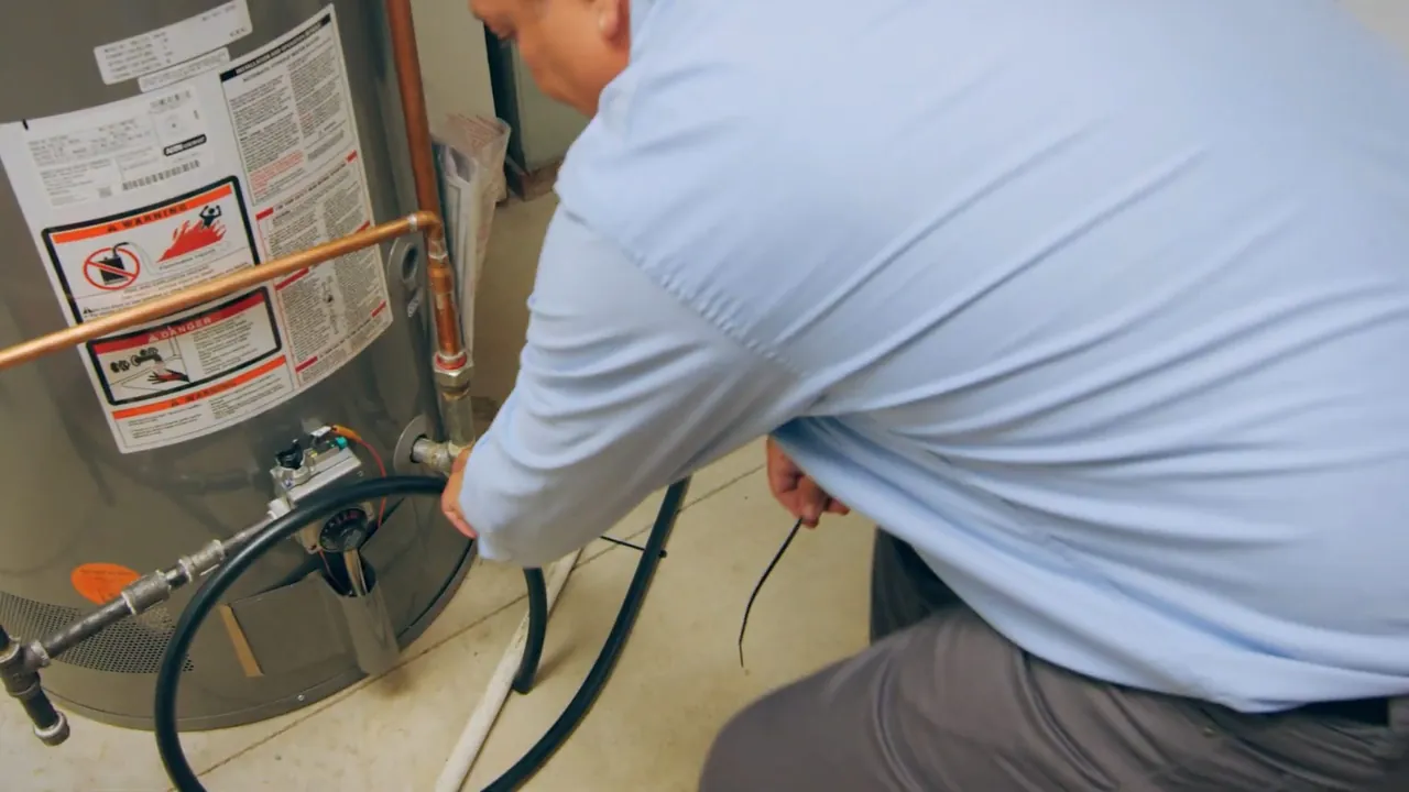 Technician attaching service hoses while flushing a residential water heater