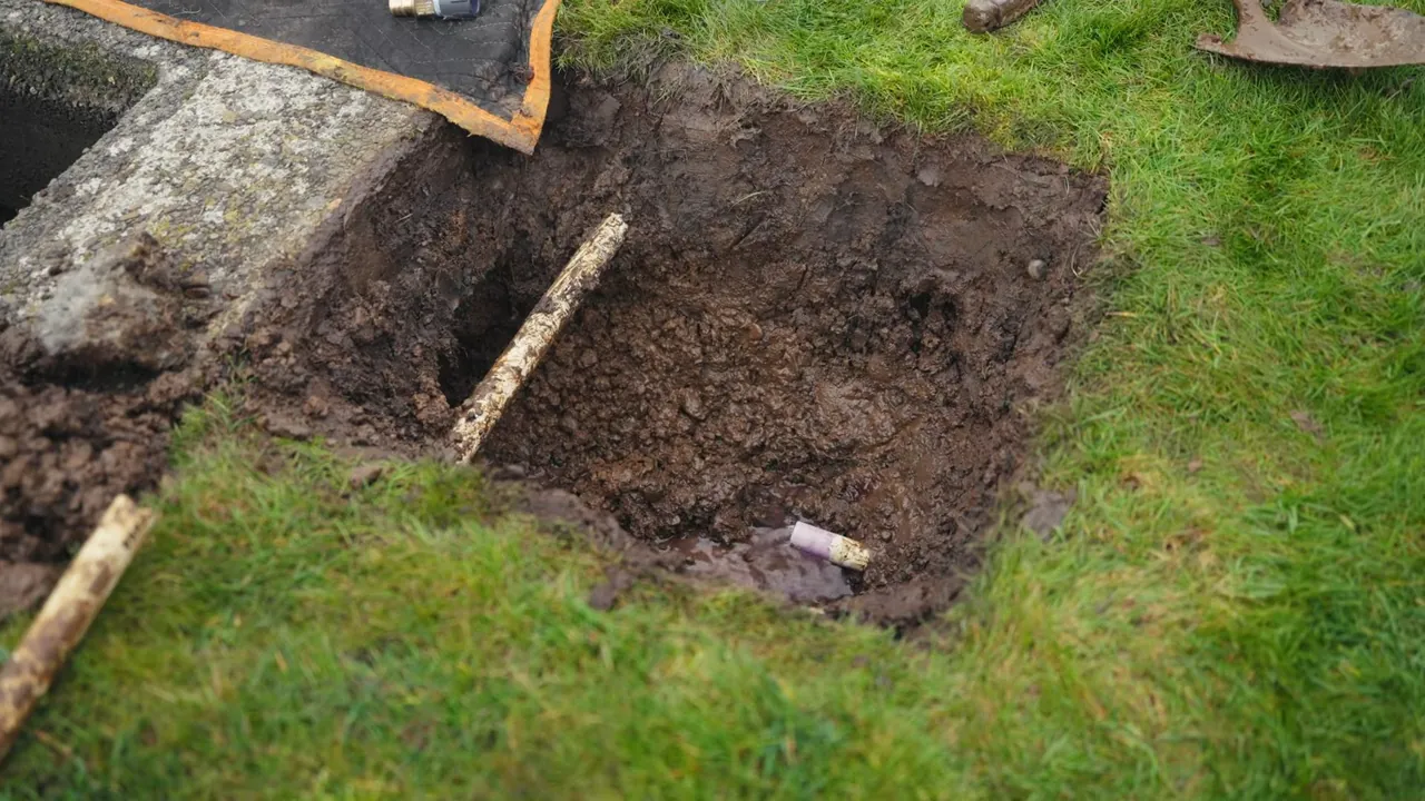 Fresh utility trench cut through a residential yard with dense soil exposed